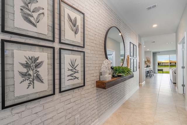 hallway featuring brick wall and light tile patterned flooring