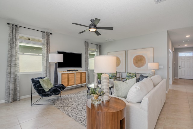 tiled living room featuring ceiling fan, a textured ceiling, and plenty of natural light