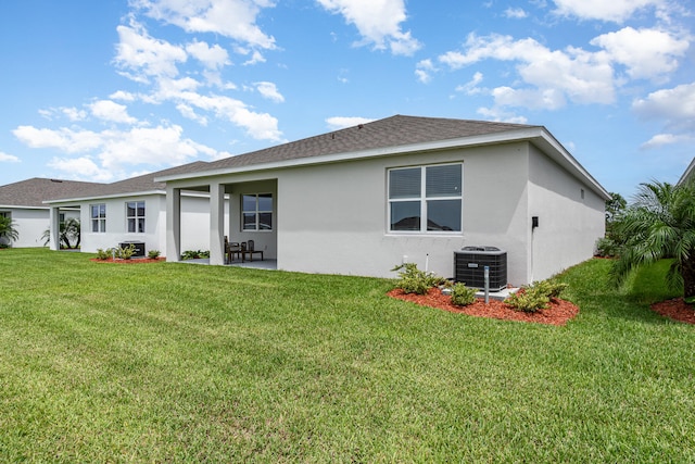 rear view of house with cooling unit, a patio area, and a yard