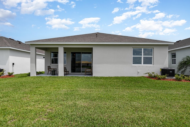 rear view of property with a lawn, cooling unit, and a patio area