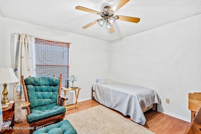 bedroom featuring light wood-type flooring, ceiling fan, and a textured ceiling