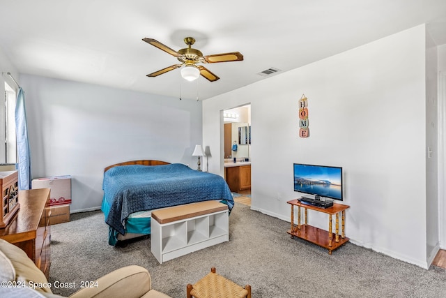 bedroom with ceiling fan, ensuite bath, and light carpet