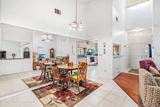 dining area with an inviting chandelier, a towering ceiling, and light hardwood / wood-style floors