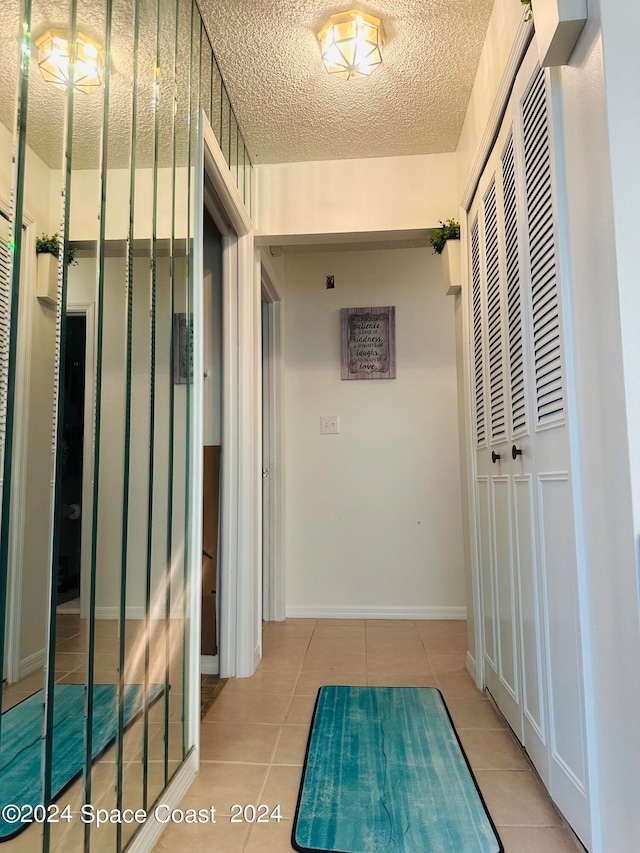 hallway featuring a textured ceiling and light tile patterned flooring