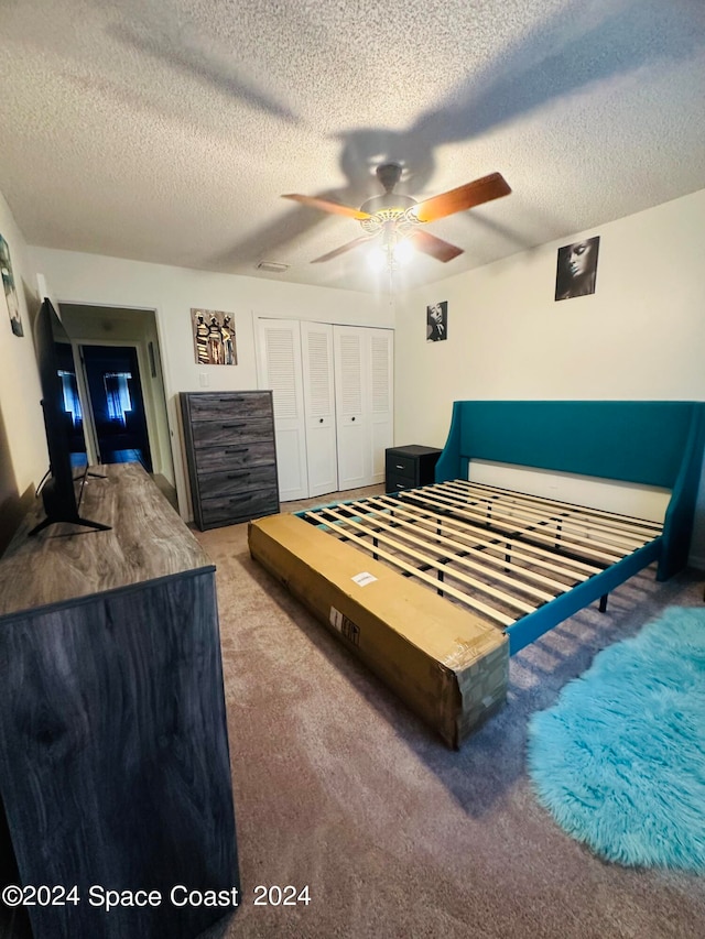 carpeted bedroom with ceiling fan, a textured ceiling, and a closet