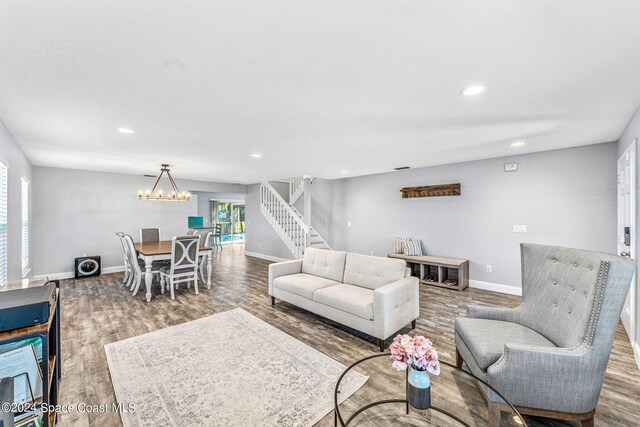 living room with stairs, wood finished floors, baseboards, recessed lighting, and a notable chandelier
