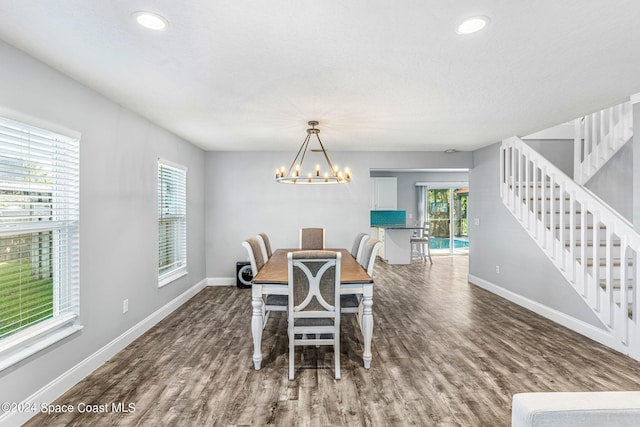 dining space with a notable chandelier, a healthy amount of sunlight, and dark hardwood / wood-style flooring