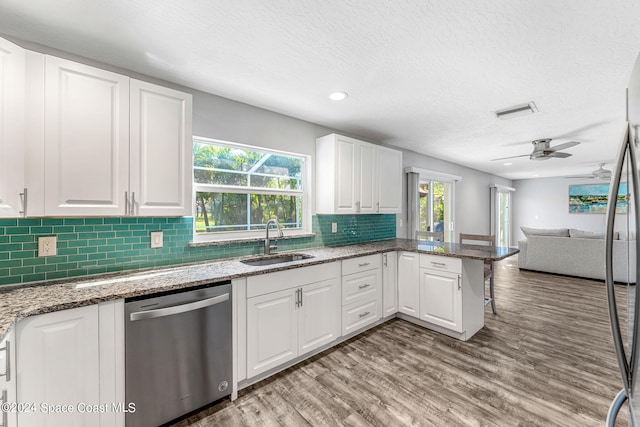 kitchen with sink, light hardwood / wood-style floors, dishwasher, and white cabinets