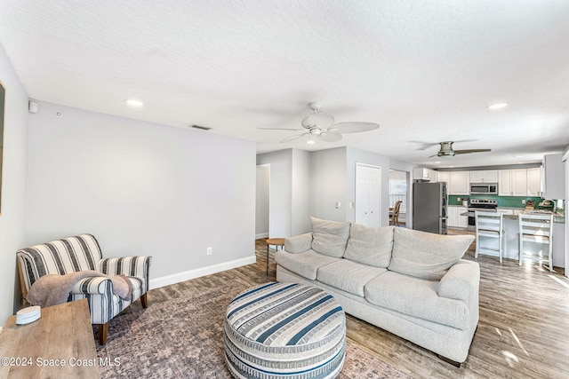 living room featuring light hardwood / wood-style floors, a textured ceiling, sink, and ceiling fan