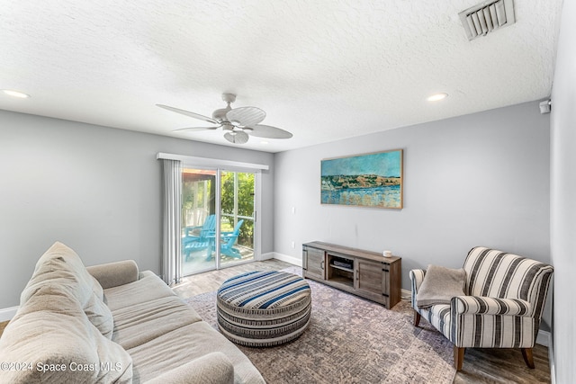 living room featuring a textured ceiling, wood-type flooring, and ceiling fan