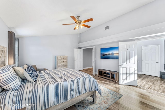 bedroom featuring visible vents, wood finished floors, baseboards, a ceiling fan, and vaulted ceiling