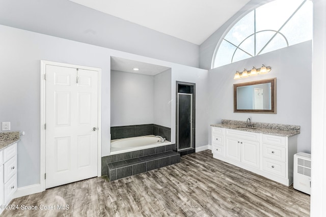 full bath featuring vanity, wood finished floors, lofted ceiling, a bath, and a stall shower