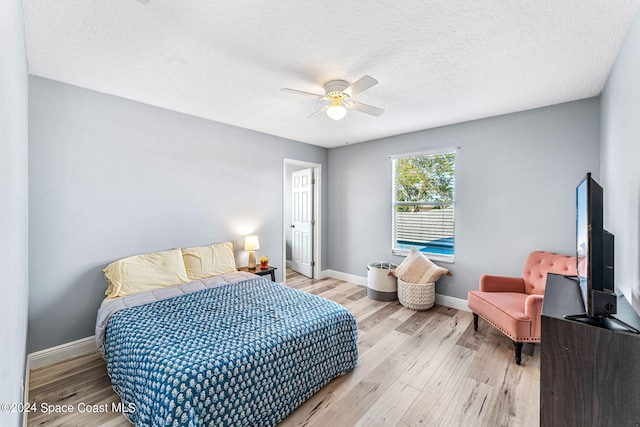 bedroom featuring a textured ceiling, light wood-type flooring, and ceiling fan