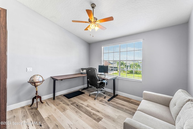 home office with baseboards, a textured ceiling, ceiling fan, and light wood-type flooring