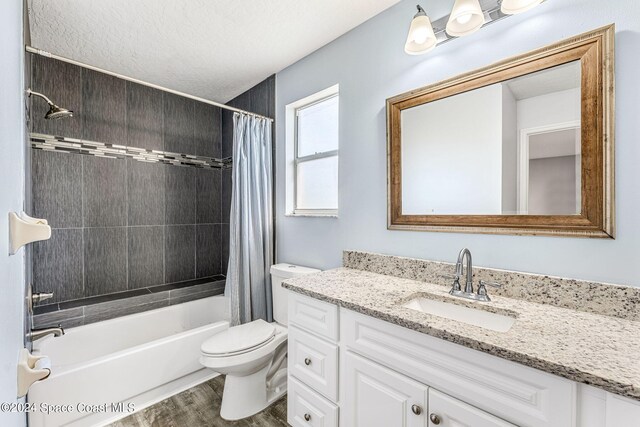 full bath with a textured ceiling, wood finished floors, vanity, toilet, and shower / tub combo with curtain
