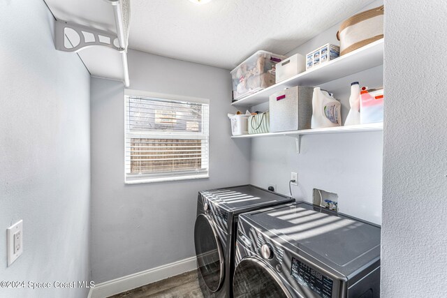 clothes washing area with laundry area, a textured ceiling, independent washer and dryer, wood finished floors, and baseboards