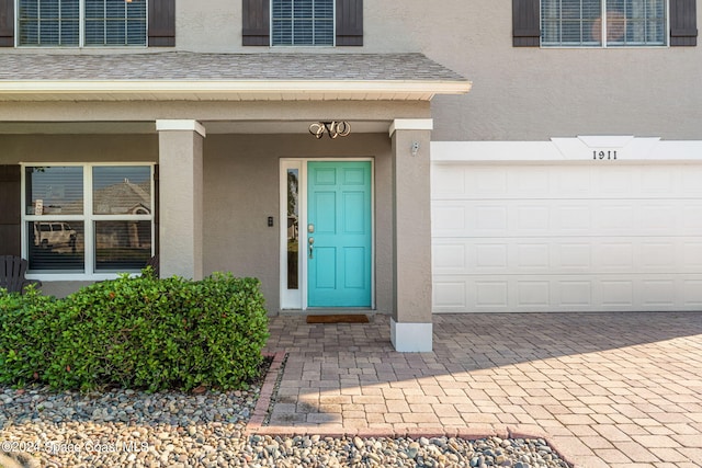 view of exterior entry featuring covered porch and a garage