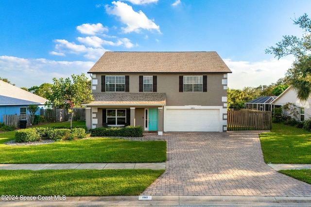 traditional home featuring a garage, decorative driveway, fence, a front lawn, and stucco siding