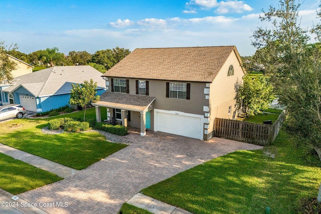 view of front of house featuring a garage, fence, a front yard, decorative driveway, and stucco siding