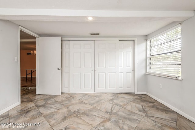 unfurnished bedroom featuring an inviting chandelier and a closet