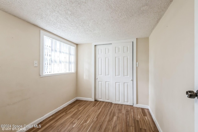 unfurnished bedroom with a closet, a textured ceiling, and hardwood / wood-style floors