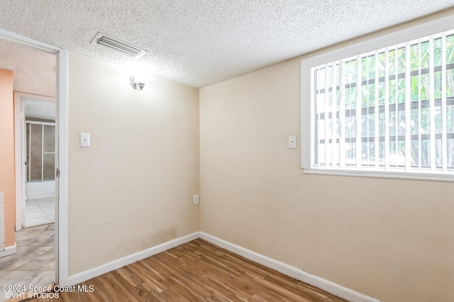 spare room featuring a textured ceiling and hardwood / wood-style flooring