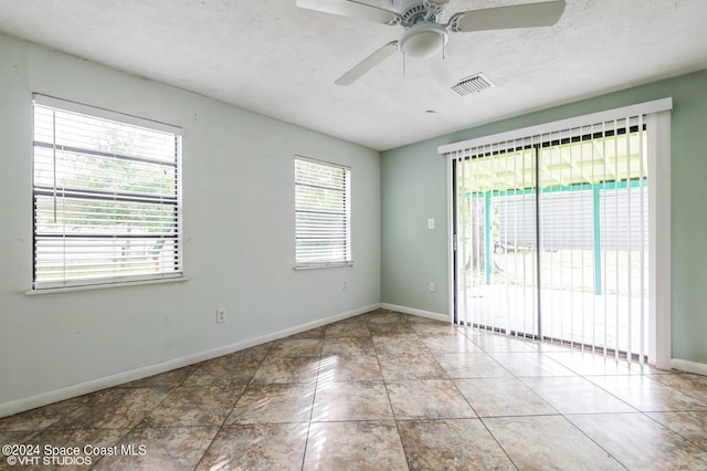 empty room with a textured ceiling, light tile patterned floors, and ceiling fan