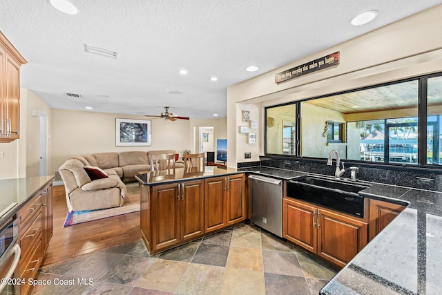 kitchen with ceiling fan, dishwasher, sink, kitchen peninsula, and a textured ceiling