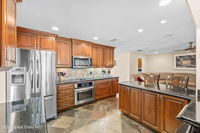 kitchen featuring ceiling fan, a textured ceiling, appliances with stainless steel finishes, and decorative backsplash