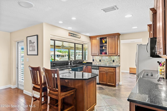 kitchen featuring dark stone countertops, a breakfast bar area, backsplash, and a textured ceiling