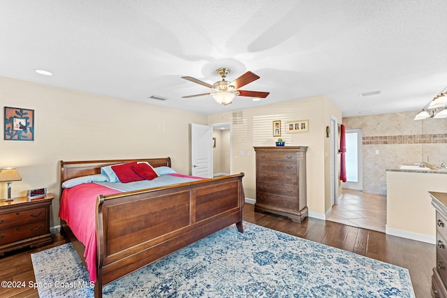 bedroom with ceiling fan, a textured ceiling, tile walls, and dark hardwood / wood-style flooring