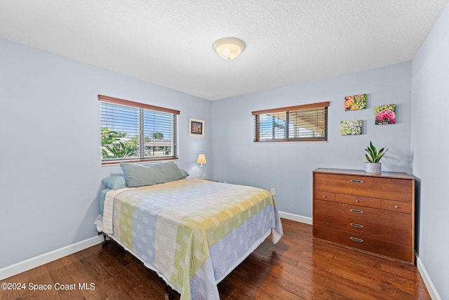 bedroom with a textured ceiling and dark hardwood / wood-style flooring