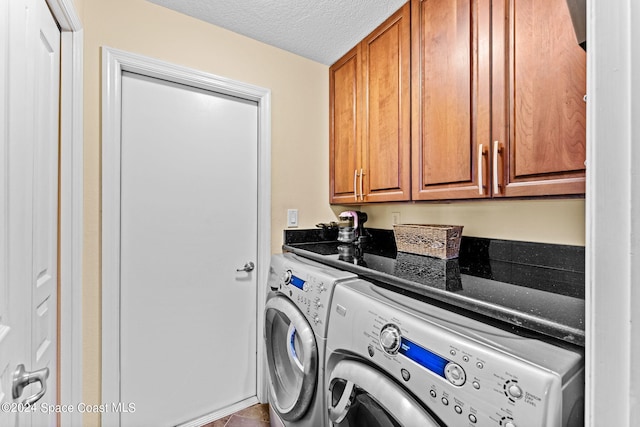 laundry area with washer and clothes dryer, cabinets, and a textured ceiling