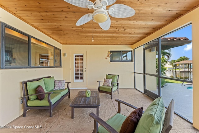 sunroom / solarium with ceiling fan, a water view, and wooden ceiling