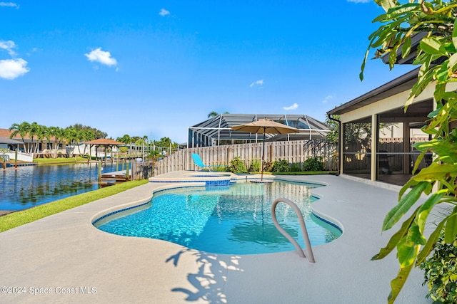 view of pool with an in ground hot tub, a water view, glass enclosure, and a patio area