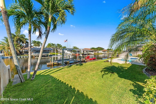 view of yard featuring a water view, a fenced in pool, and a boat dock