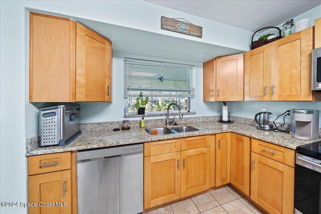 kitchen featuring light stone counters, stainless steel appliances, sink, light tile patterned floors, and a textured ceiling