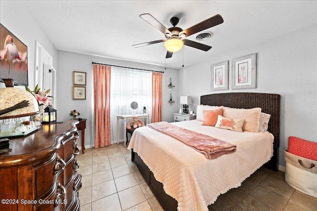 bedroom featuring baseboards, visible vents, light tile patterned floors, and ceiling fan