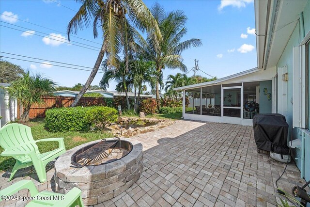 view of patio / terrace featuring a fire pit, grilling area, and a sunroom