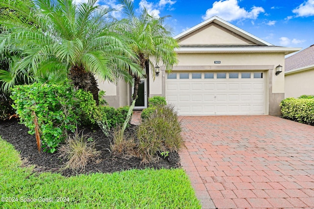 view of front facade with a garage, decorative driveway, and stucco siding