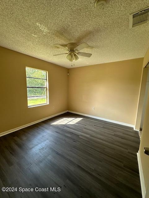 empty room featuring dark hardwood / wood-style floors, a textured ceiling, and ceiling fan