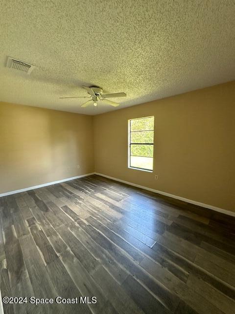 empty room featuring ceiling fan, dark hardwood / wood-style floors, and a textured ceiling