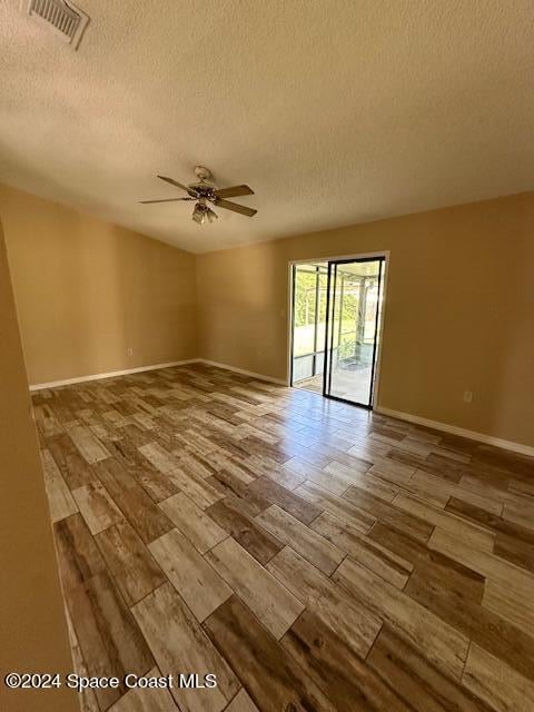 empty room with a textured ceiling, ceiling fan, and light hardwood / wood-style flooring