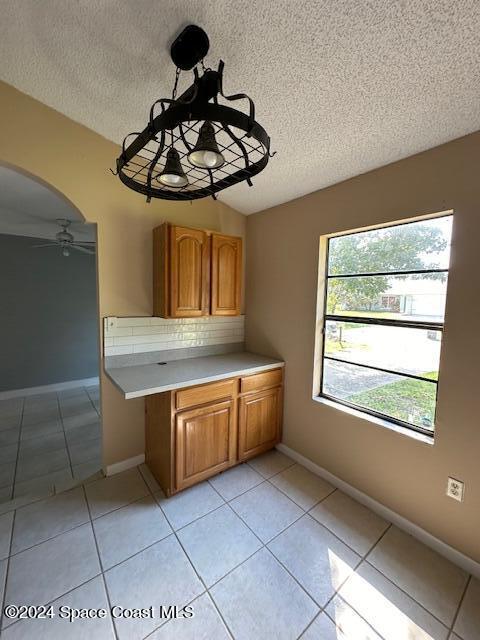 kitchen featuring pendant lighting, light tile patterned floors, a textured ceiling, and ceiling fan