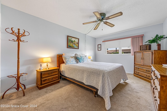 bedroom featuring a textured ceiling, ceiling fan, and light colored carpet