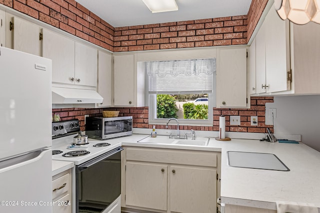 kitchen featuring brick wall, sink, and white appliances