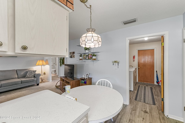 dining room with a textured ceiling, light hardwood / wood-style floors, and independent washer and dryer