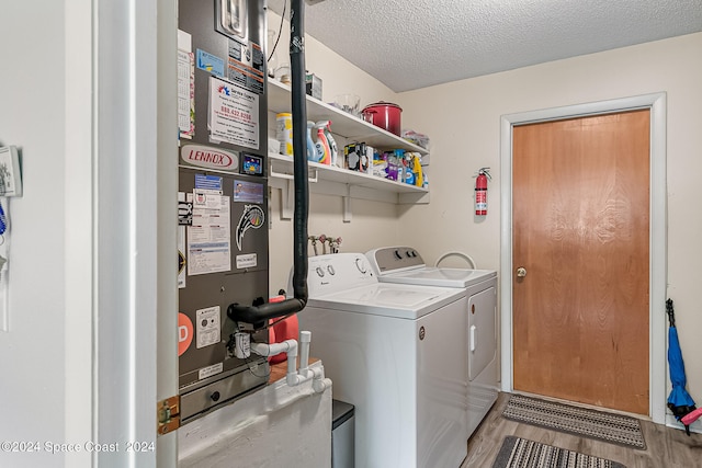 clothes washing area with wood-type flooring, a textured ceiling, and washing machine and dryer