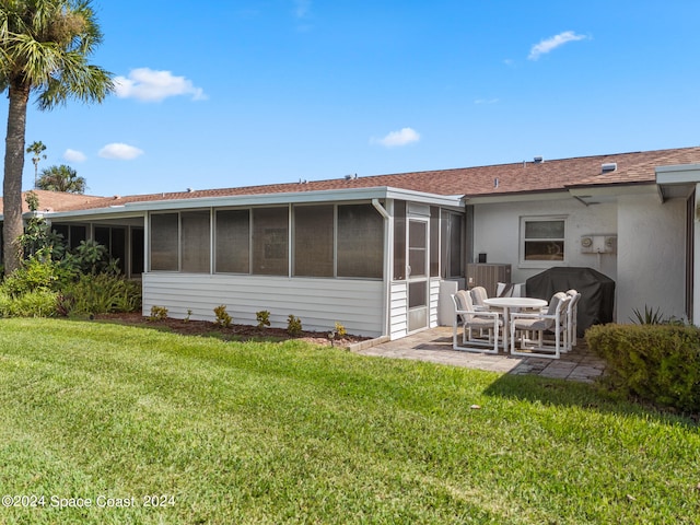 back of property featuring a patio, a lawn, and a sunroom