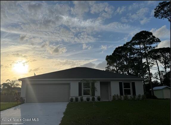 ranch-style home featuring driveway, a front yard, an outbuilding, a storage unit, and an attached garage